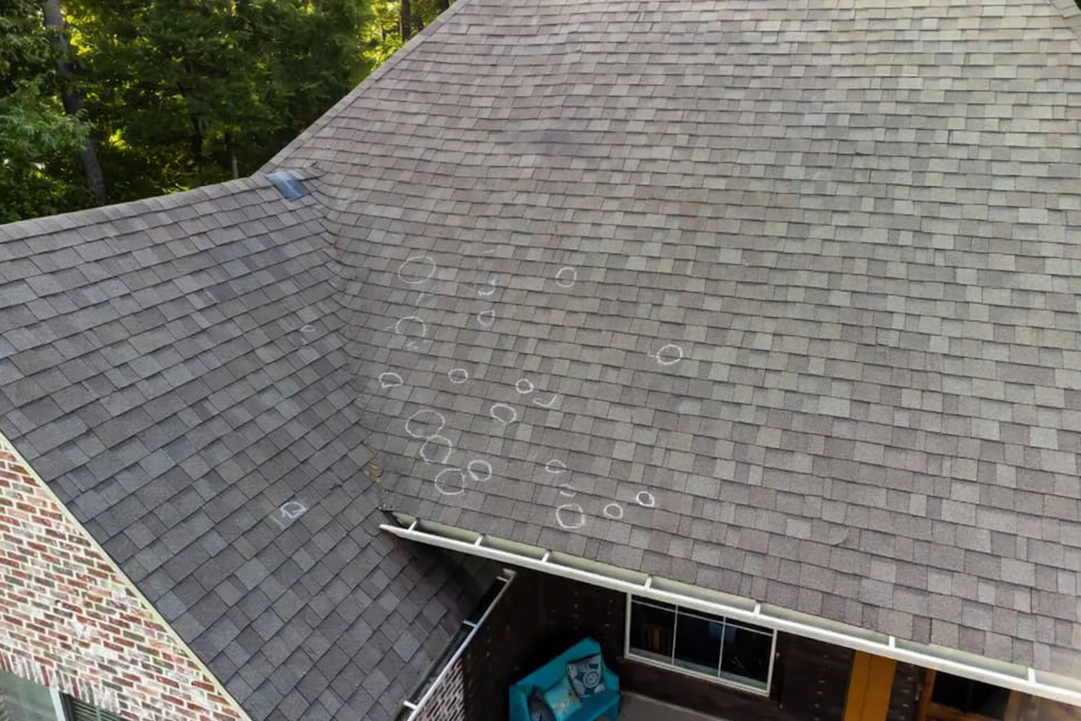 Hail-damaged roof shingles — bruised and cracked asphalt from impact